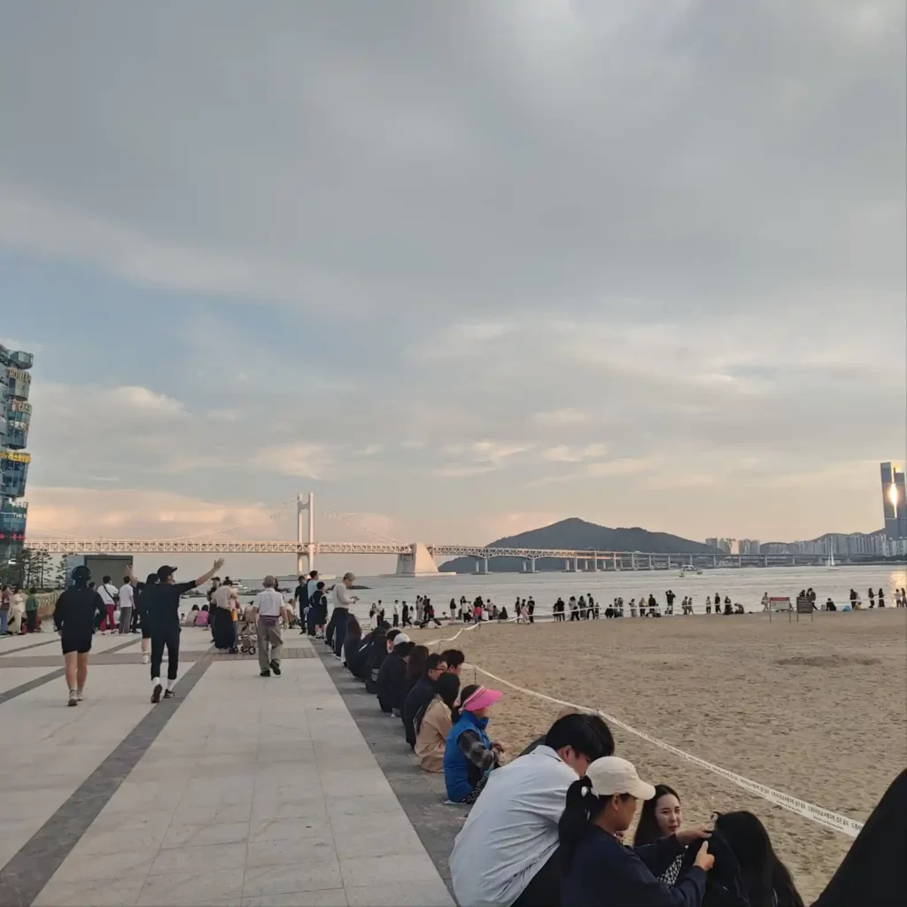 광안리 해변에 앉아 있는 사람들과 하늘, 그리고 광안대교